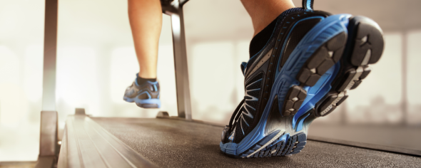 Person walking/jogging on a treadmill; only feet and treadmill base shown.