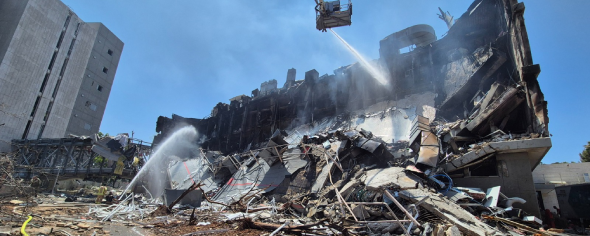 Firefighters hose down the charred and ruined remains of a research building at Weizmann Institute